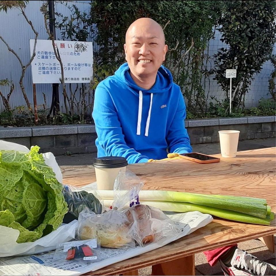 野菜が並ぶテーブルで笑顔を見せる松本誠二さん